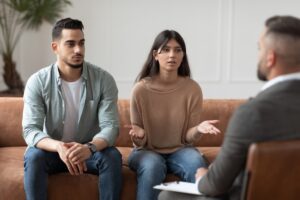 Portrait of serious young lady talking to psychologist counselor complaining on bad relationship with husband, family couple counseling having conversation about problem at therapy session.