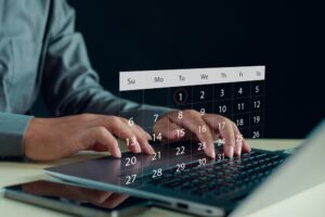 Hands typing on laptop with transparent digital calendar overlay, symbolizing online scheduling, time management, task planning, productivity workflow, deadline reminders, organized work routines.