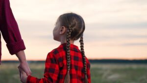 Daughter parent holding hands at sunset.