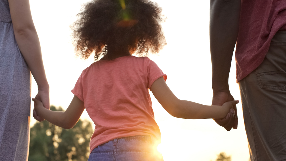 Little girl holds fathers and mothers hands, happiness and wellbeing in family