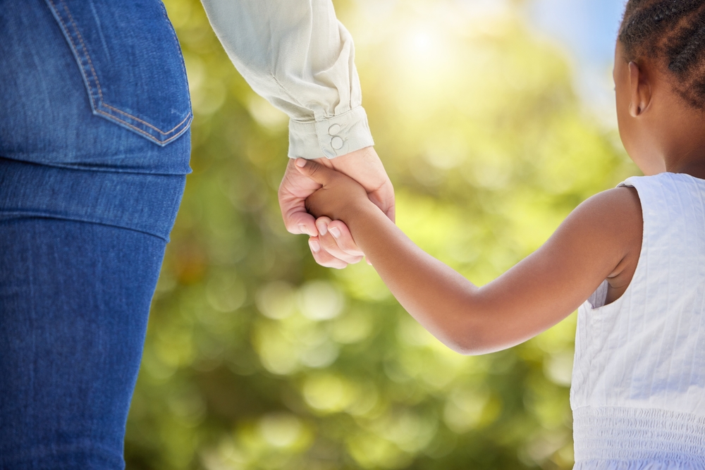 Child, parent and holding hands in outdoor closeup for walking park, support and trust with care for enjoy nature sunshine.