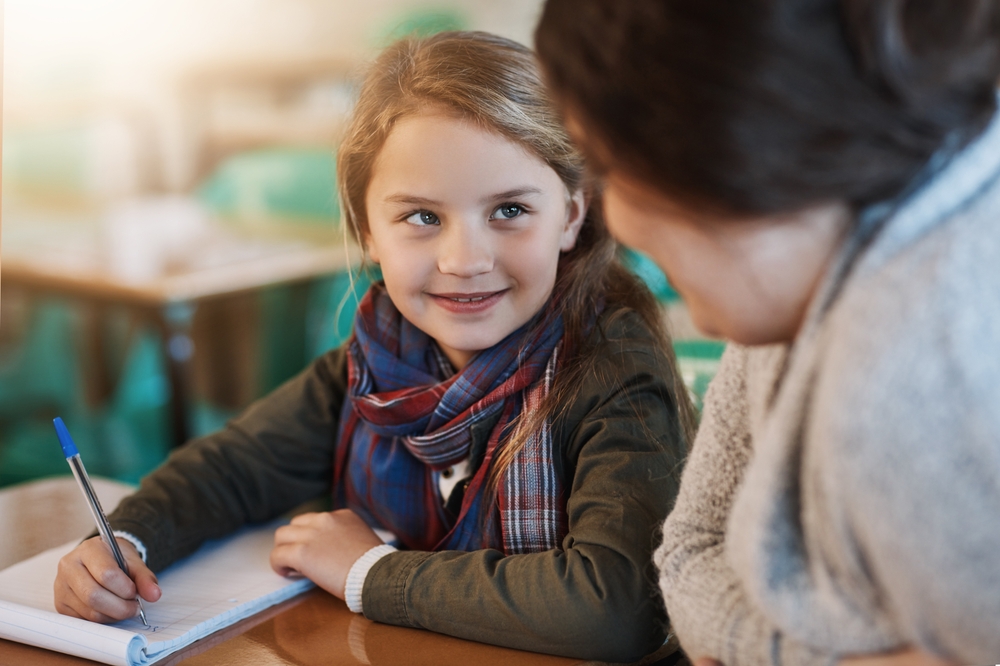 Teacher, learning and help child writing in notebook for education, study or knowledge in class.