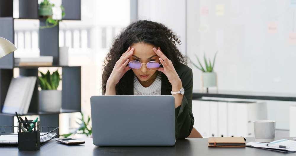 Business, headache and woman in office, laptop and tired with fatigue, financial agency and exhausted.