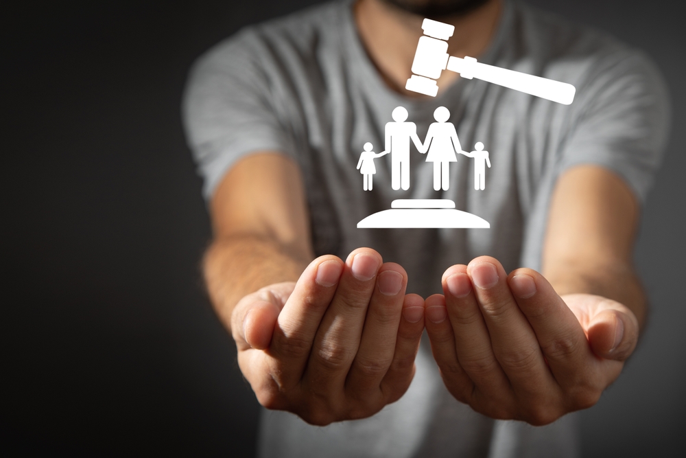 Male hand holding judge gavel with a family symbol.