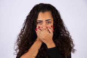 Brazilian woman, curly hair, fear, domestic violence, fight against feminicide. Hands over mouth, silence.