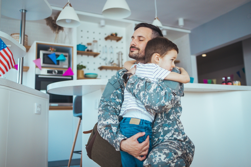 Military man father hugs son.