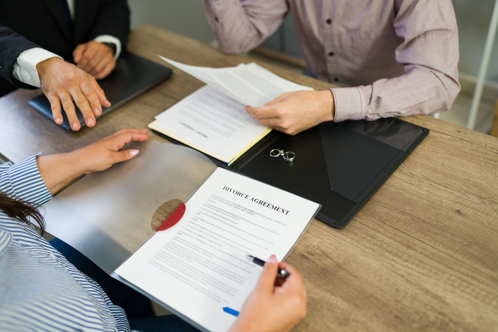 Couple concluding their marriage and signing a legal divorce agreement with an attorney or lawyer present.