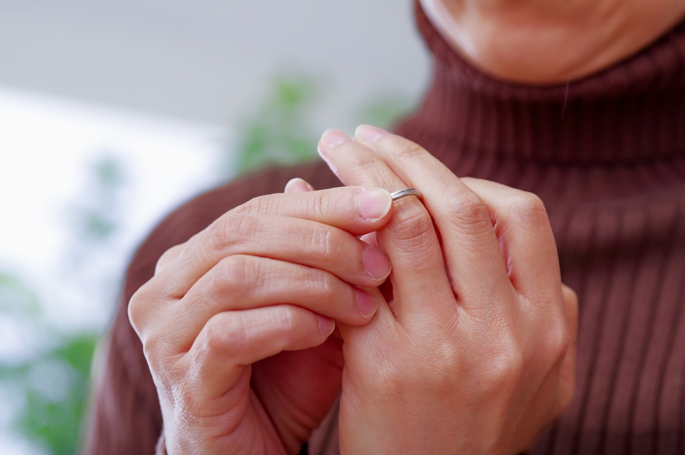 A woman removing the ring on her left hand.