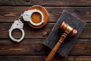 Metal handcuffs with judges gavel and criminal code book.