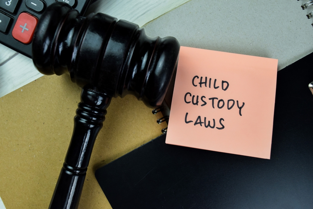 Concept of Child Custody Laws write on sticky notes with gavel isolated on Wooden Table.