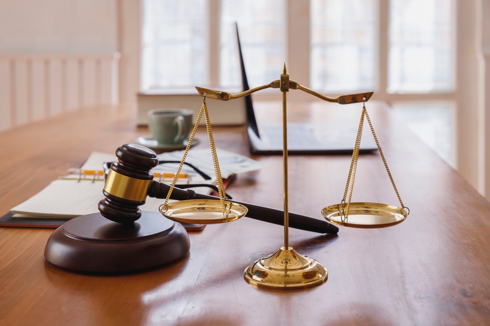 A gavel and scales of justice on a wooden desk symbolize the balance and authority of the legal system.
