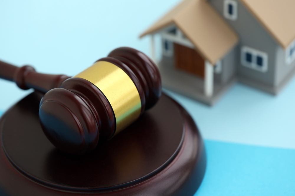 Generic toy house and judgement hammer on blue background close up