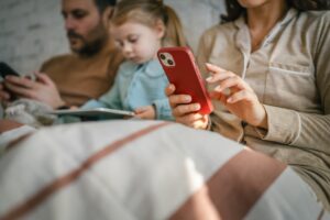 Family members, mother, father and young child, engaging with individual mobile devices, creating a scene of digital disconnection and screen addiction within the comfort of their home