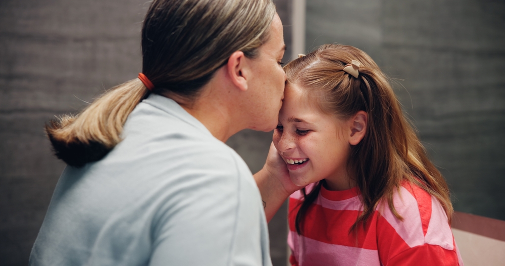 Mother, child and kiss on forehead in home for love, support and daughter bonding together with parent.