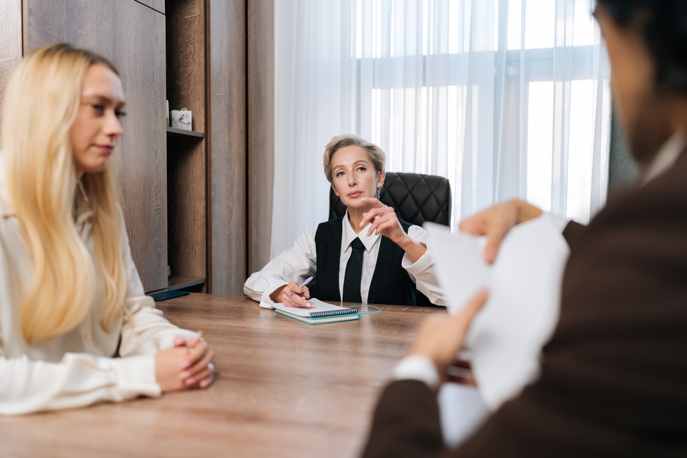 Sad couple writing documents with lawyer in agreement, application or signing legal paperwork at office.