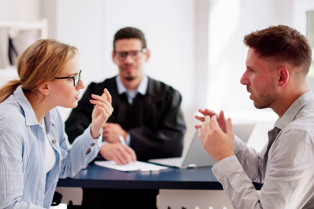 Young couple arguing in front of male judge, contemplating divorce. Family lawyer deals with their dispute, hoping for resolution.