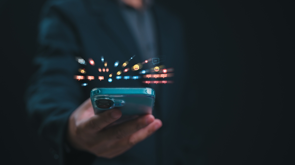 Digital Engagement Explosion Hand Holding Smartphone Shows Social Media Influence, Glowing Icons Of Likes, Comments Hearts Bursting From Screen, Driving Business Activity On Platform