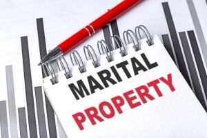 MARITAL PROPERTY text on a notebook on chart with pen.