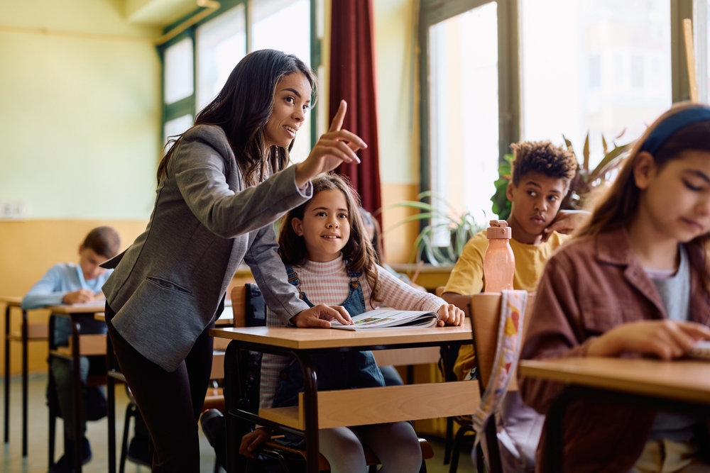 Hispanic elementary school teacher explaining a new lecture to her students during a class.