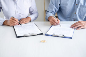 Contract decree of divorce (dissolution or cancellation) of marriage, husband and wife during divorce process and signing of divorce contract, Wedding ring.