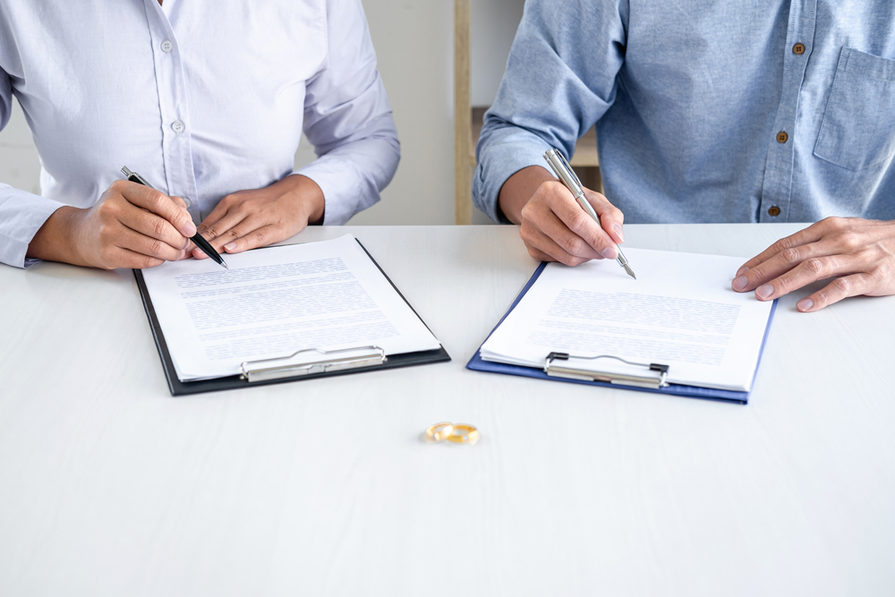 Contract decree of divorce (dissolution or cancellation) of marriage, husband and wife during divorce process and signing of divorce contract, Wedding ring.