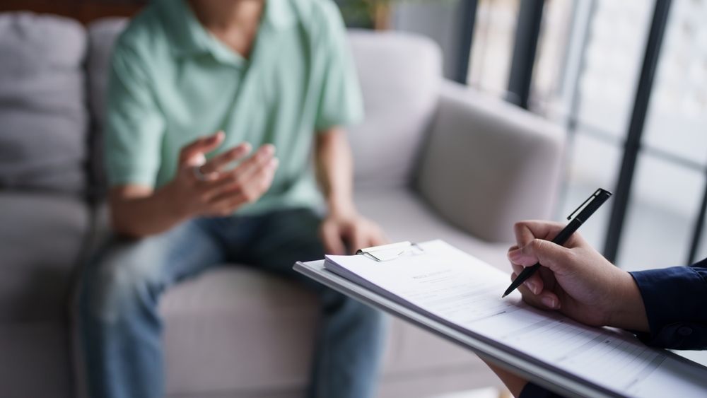 sad male sitting on sofa Patient discussing mental health issues with psychologist. depressed asian man mental health treatment concept.