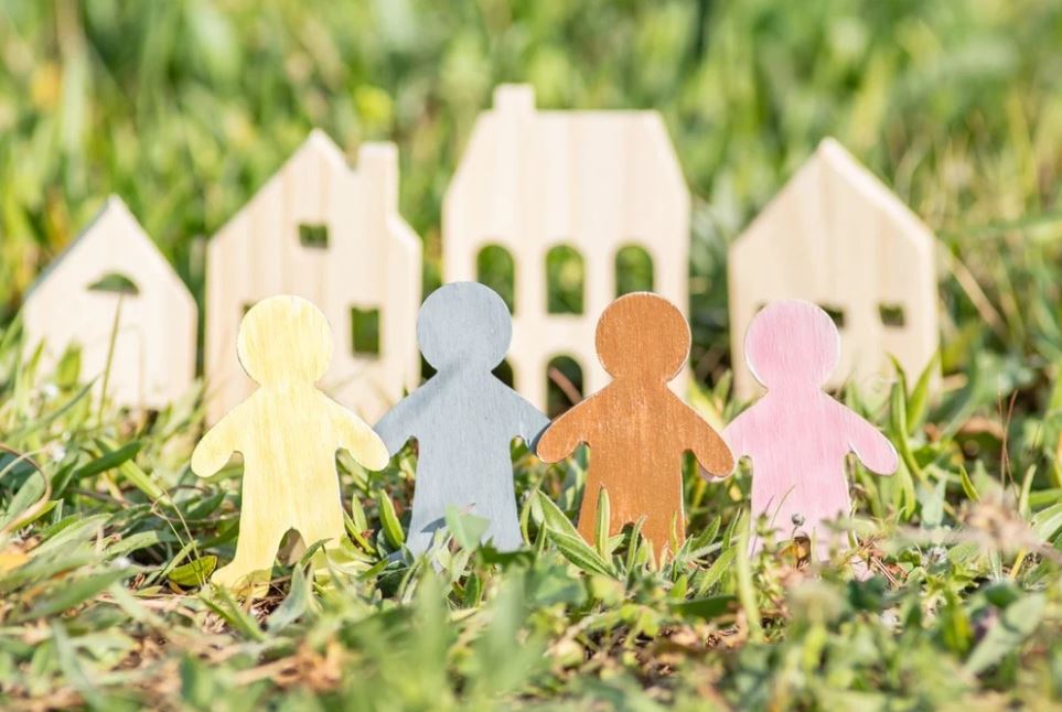 Colorful wooden figures of people holding hands in front of a wooden house. A divorce lawyer can help families determine who gets the house in a divorce with kids.